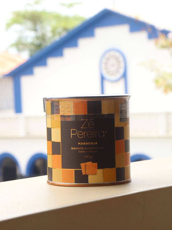 Lata de biscoito Zé Pereira com uma igrejinha azul e branca ao fundo